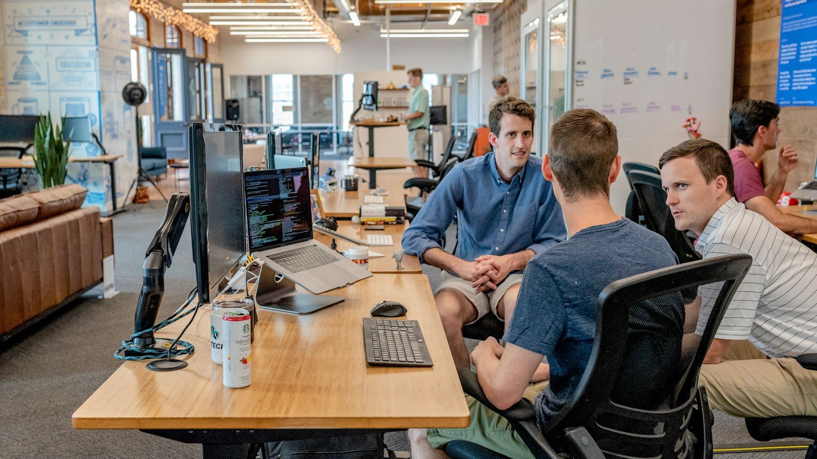 Three people talking around a desk in an open office